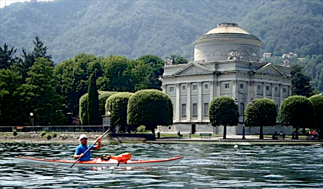 Photo of Kayaker on Lake Como paddling by an old building.
